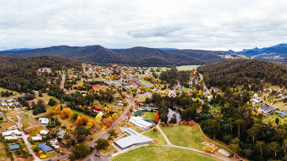 Eine Luftaufnahme einer Stadt, umgeben von Bergen und Herbstlaub.