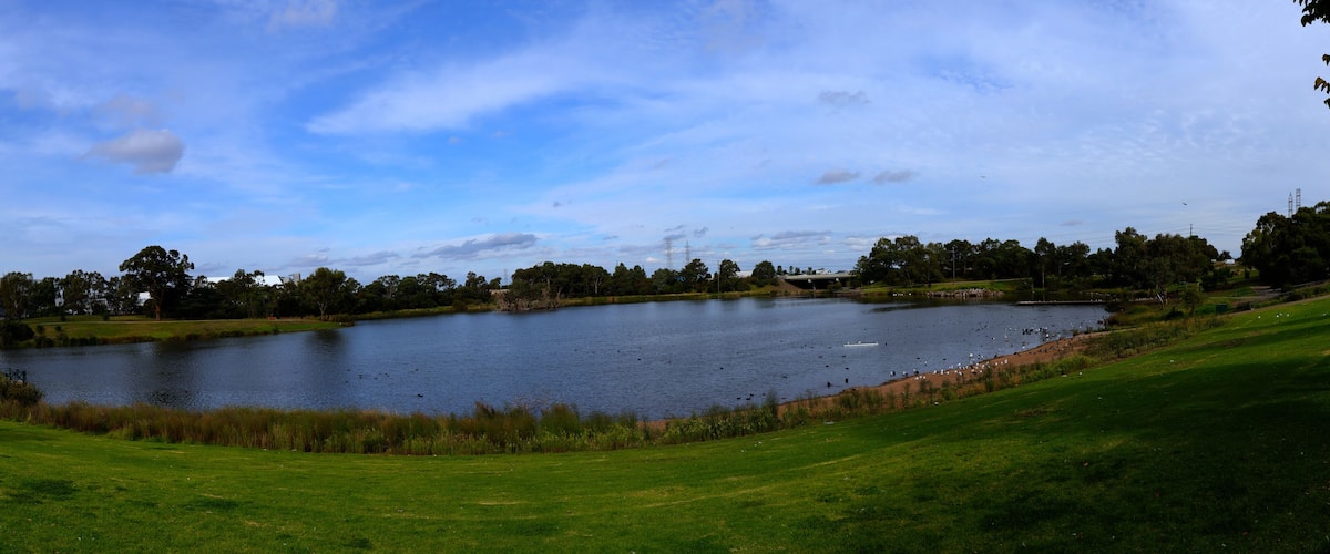Ein See, umgeben von einem Golfplatz, mit blauem Himmel.