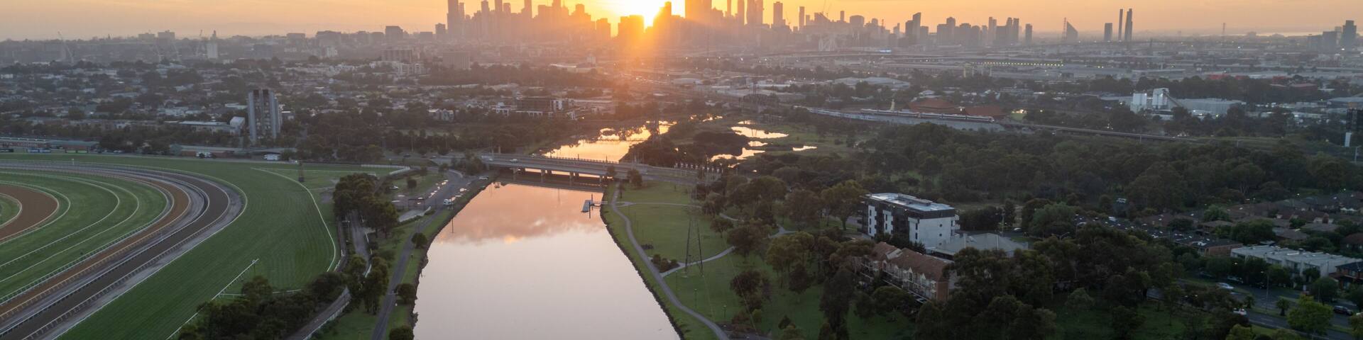 A sunset over a city skyline with a river in the foreground.