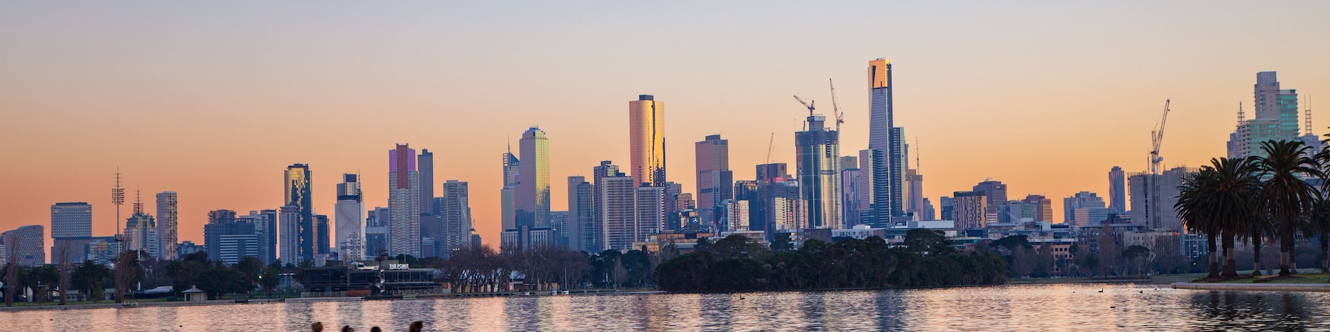 A sunset over a city skyline with a rowboat with people on it.