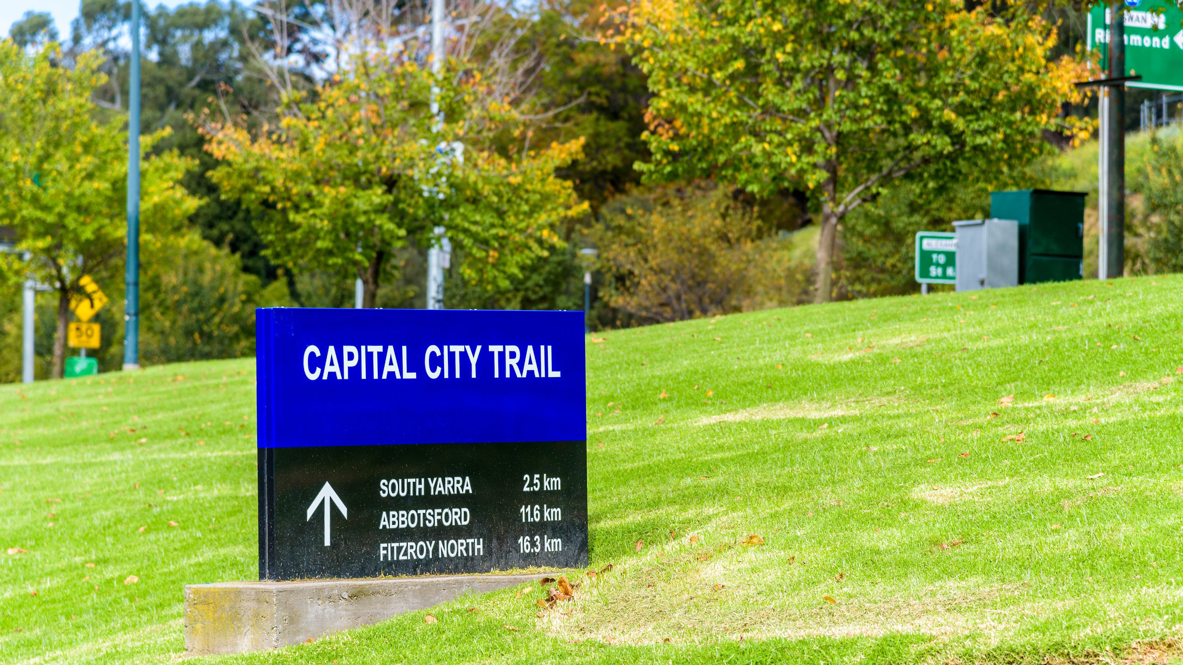 The blue and black sign for the Capital City Trail next to the Yarra River in the city of Melbourne, Australia