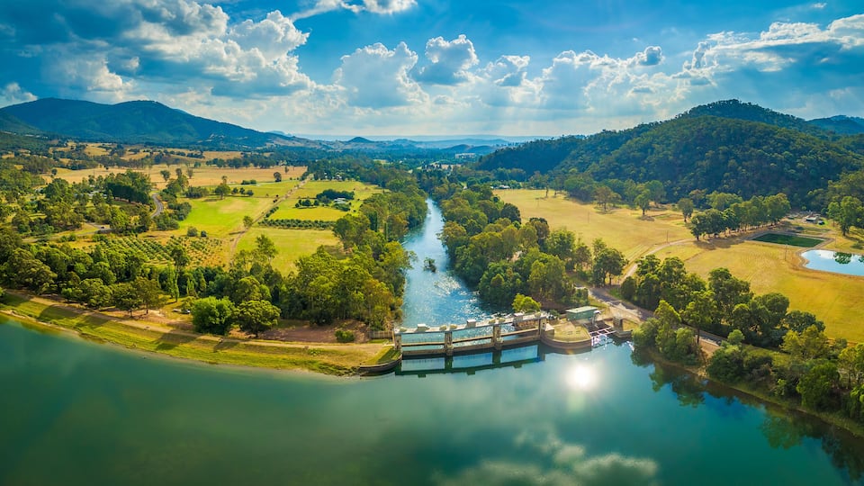 A river flowing through a valley with a dam and surrounding greenery.