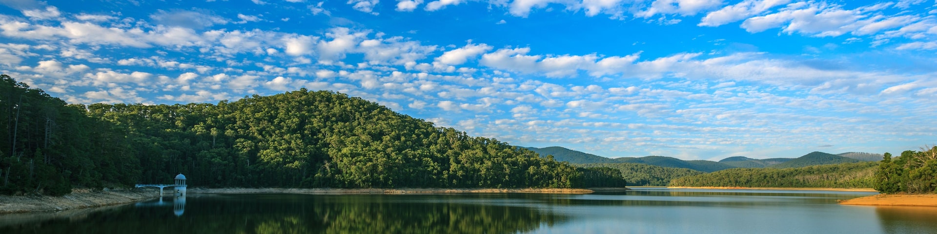 A calm lake reflecting the sky and surrounding forest.