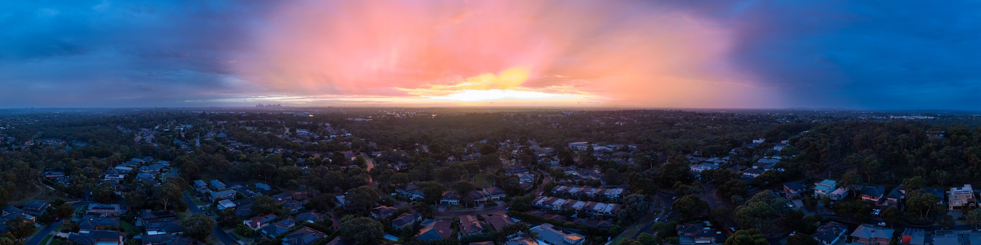 Un atardecer sobre una zona residencial con casas y árboles.
