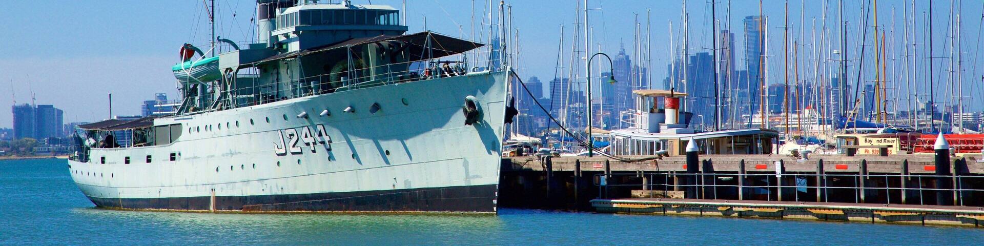 A large ship docked at a marina with a city skyline in the background.