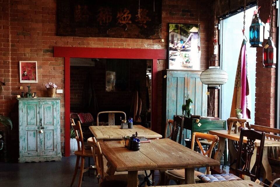 Un interno rustico con tavoli e sedie di legno, una parete in mattoni e un lampadario tradizionale.