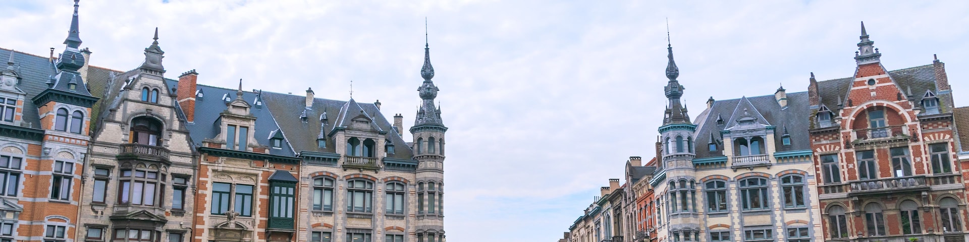 Une rue bordée de bâtiments historiques aux façades richement décorées et surmontés de flèches.