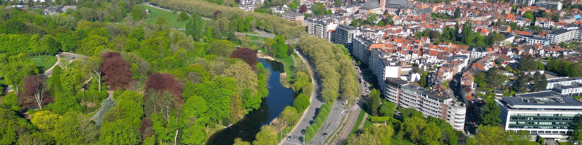 An aerial view of a city with a river, green parks, and a mix of modern and traditional architecture.