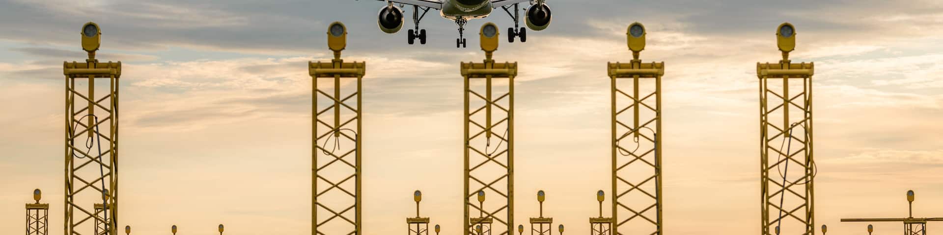 Backview of an airplane landing on Brussels airport during sunset. Runway lights in the foreground. Travel, transport theme. Big jetliner during landing at the airport.