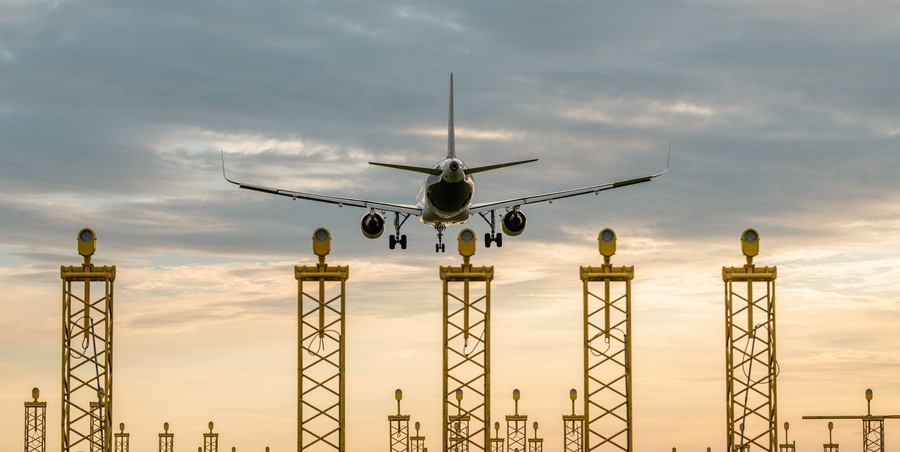 Backview of an airplane landing on Brussels airport during sunset. Runway lights in the foreground. Travel, transport theme. Big jetliner during landing at the airport.