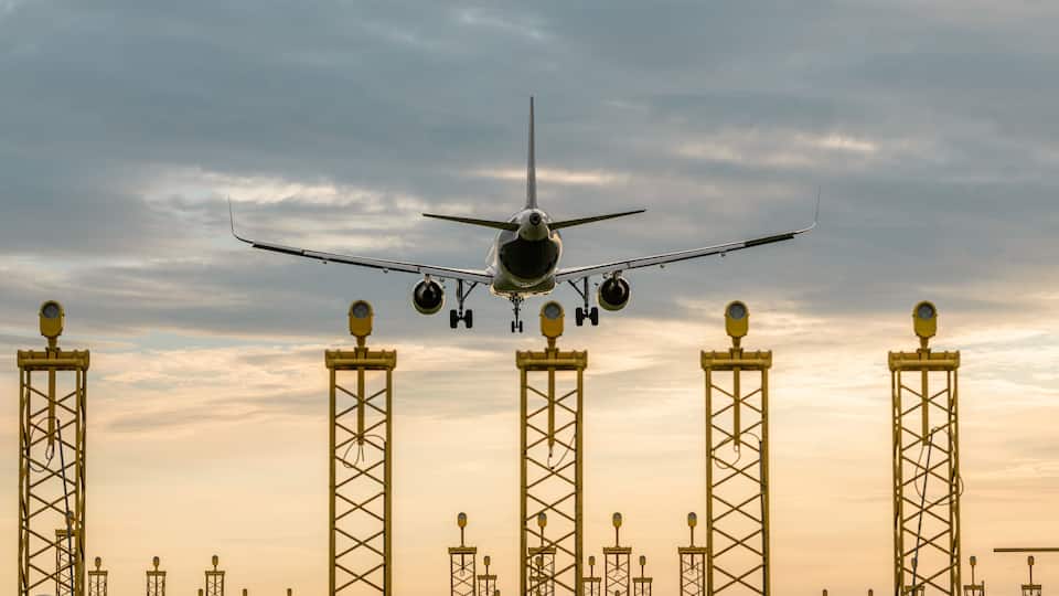 An airplane approaching a runway with multiple tall structures with lights.