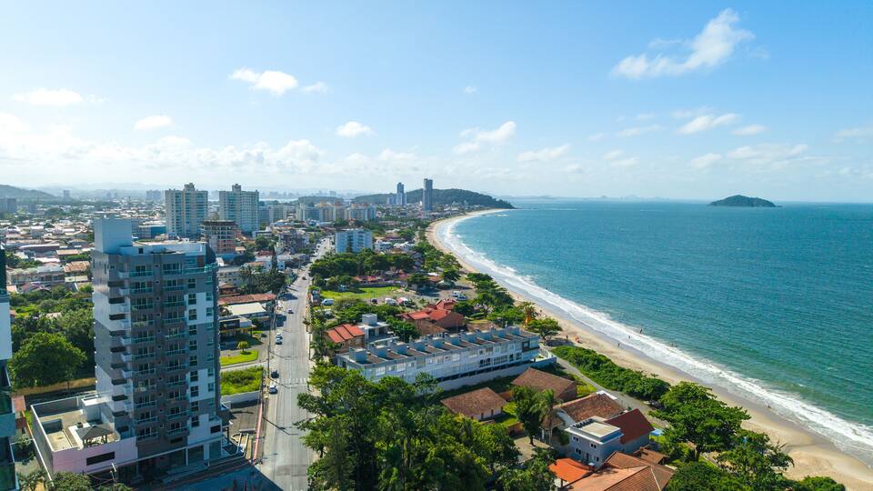 A coastal cityscape with high-rise buildings, a beach, and a distant island.