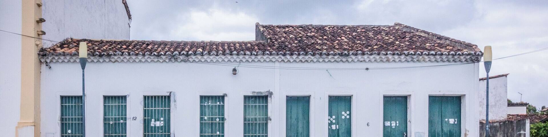 A white building with green shutters and a tiled roof.