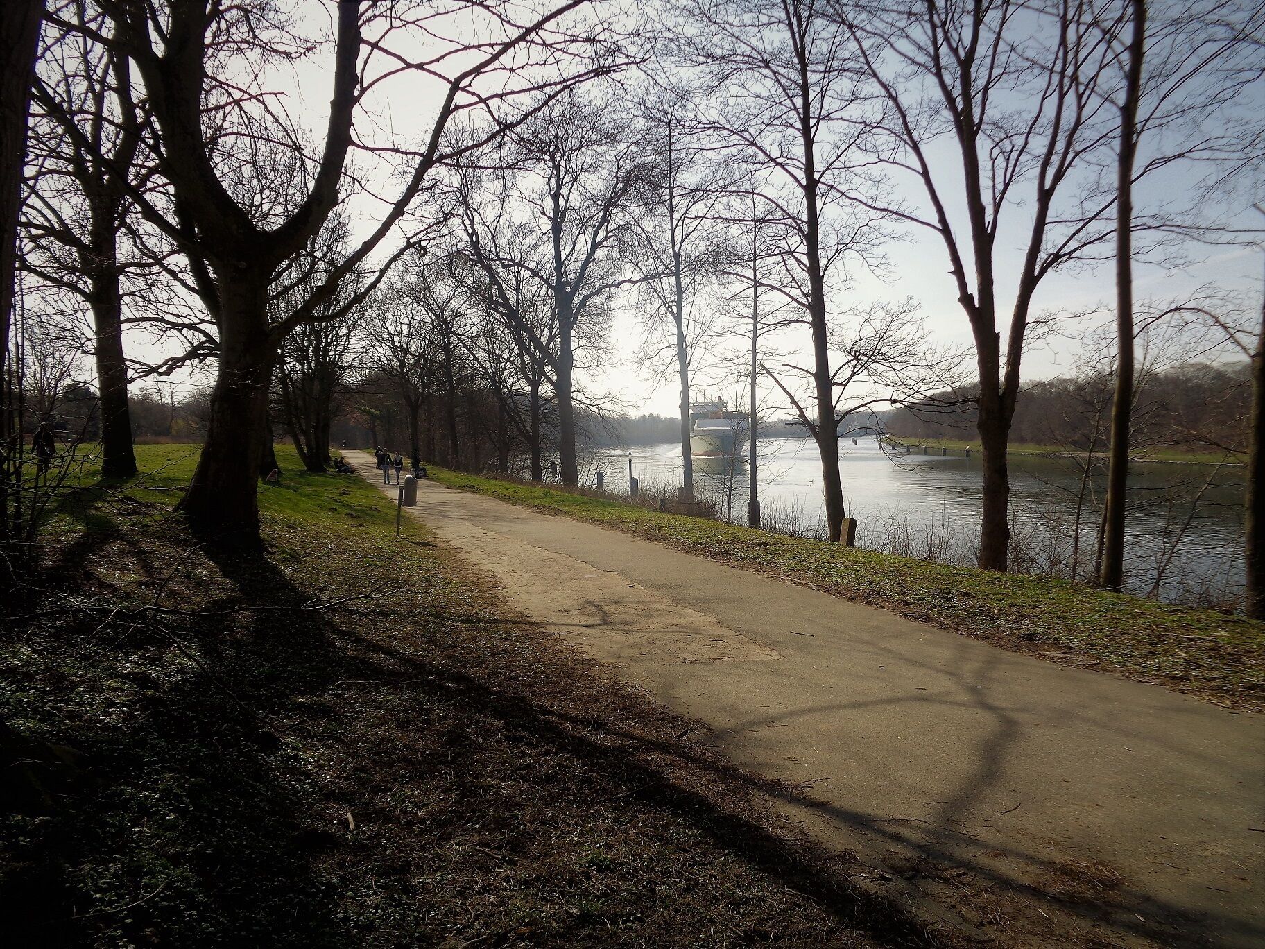 Der Wanderweg Am Kanal in Kiel-Suchsdorf. Rechts hinten das Containerschiff "Heinrich Ehler" im Nord-Ostsee-Kanal, Höhe Kanalweiche.