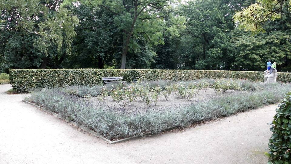 A well-maintained garden with a variety of plants, a bench, and a statue.