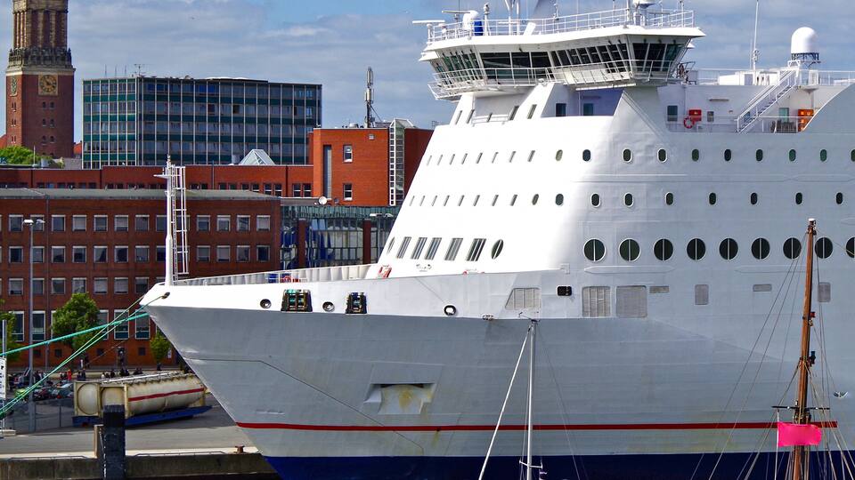 Passenger ferry Stena Line with sailing boats in port of Kiel, Germany with clocktower of cathedral and buildings in background during Kieler Woche Sailing Week