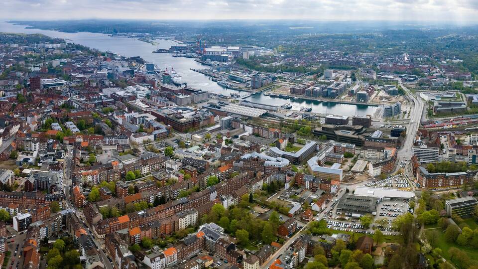 An aerial view of a city with a river, bridges, and a large stadium.