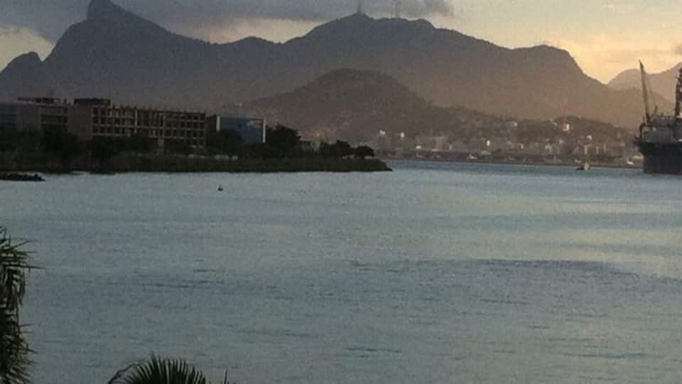 A coastal cityscape with mountains in the background and a body of water in the foreground.
