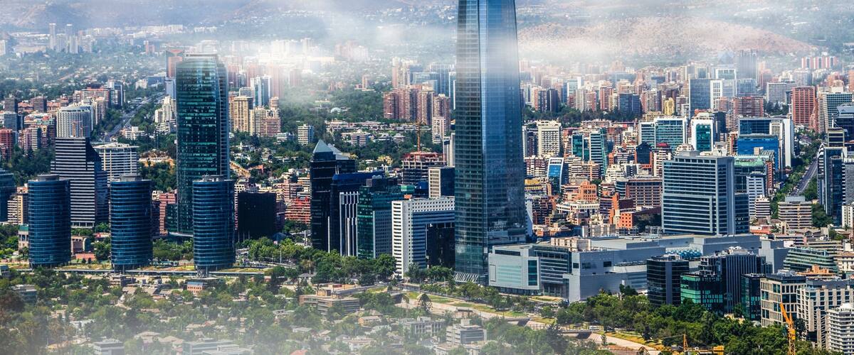 Une vue urbaine avec des gratte-ciel modernes et une chaîne de montagnes en arrière-plan.