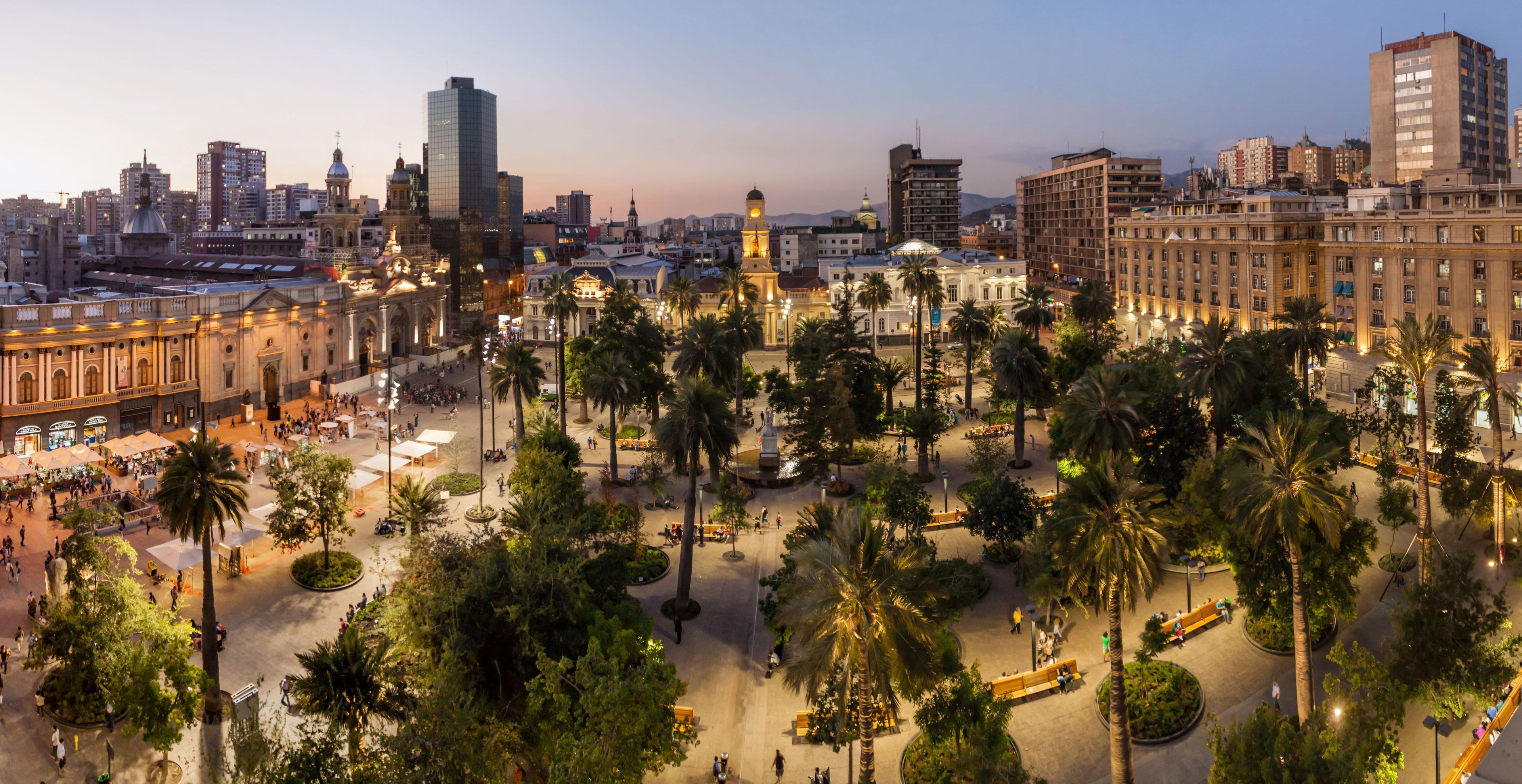 A cityscape with a prominent historical building, palm trees, and modern high-rise buildings.