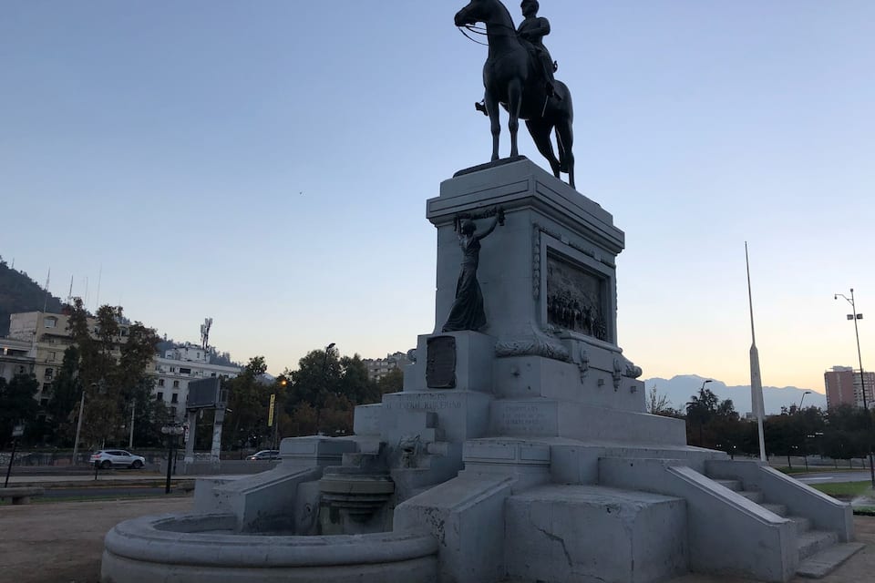 Een standbeeld van een ruiter, een fontein en een monumentale sokkel met inscripties.