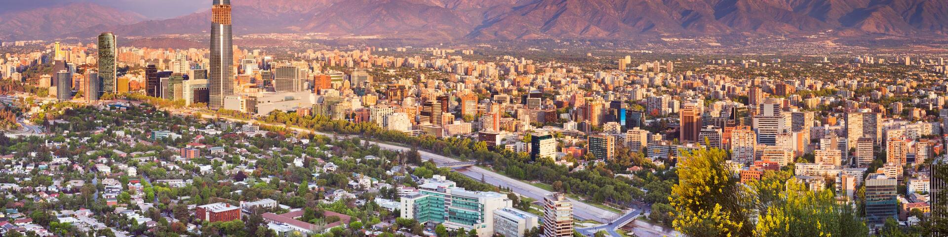 A cityscape with a prominent skyscraper, dense urban buildings, and a mountain range in the background.