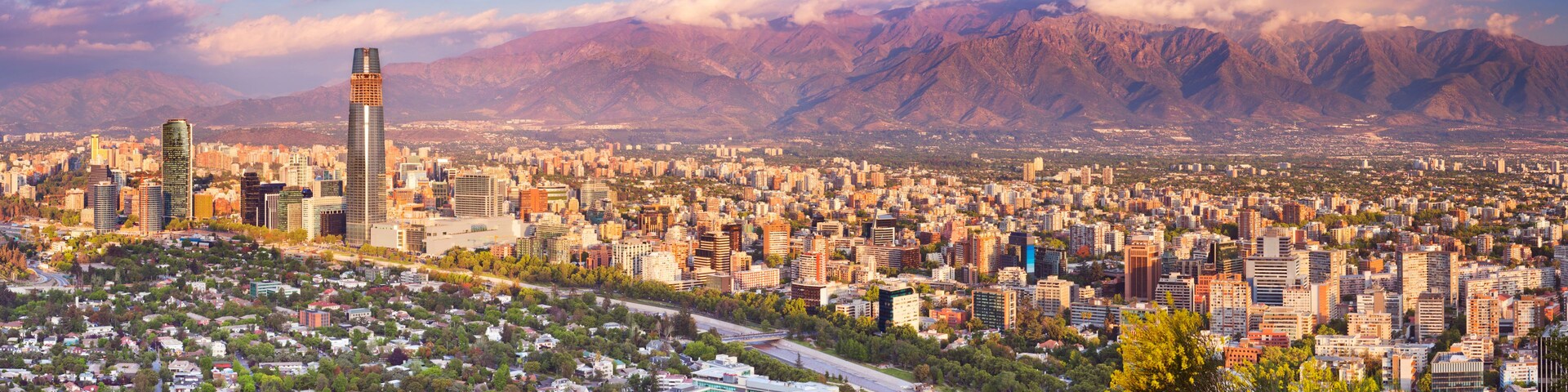 A cityscape with a prominent skyscraper, dense urban buildings, and a mountain range in the background.