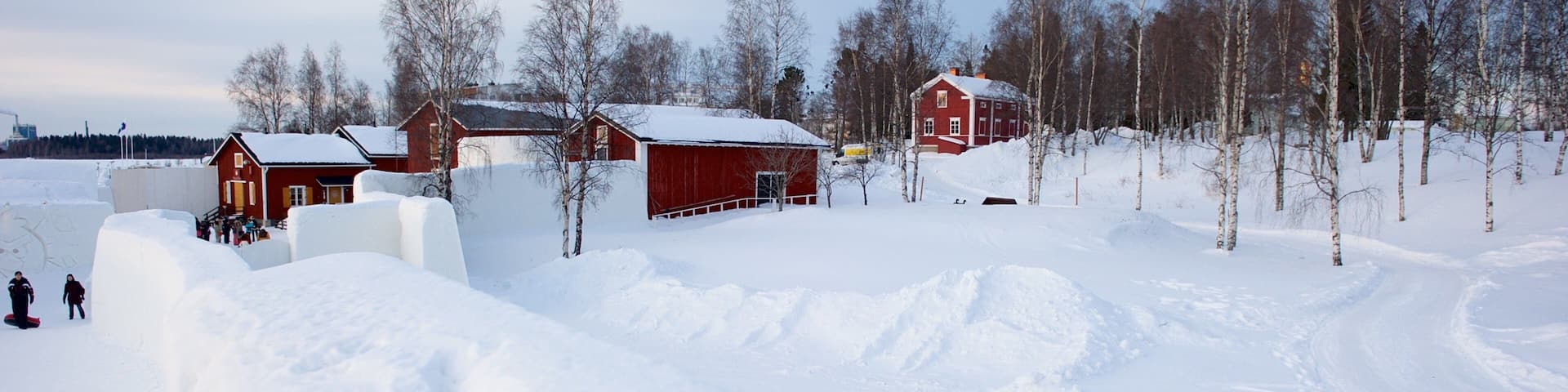 A snowy landscape with red barns and birch trees.