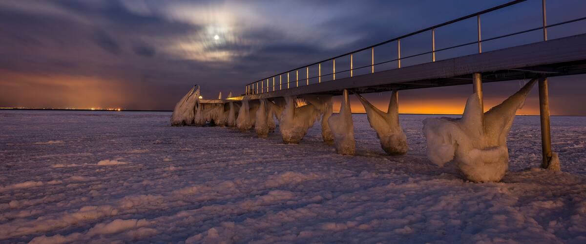A frozen landscape with a bridge and ice formations.