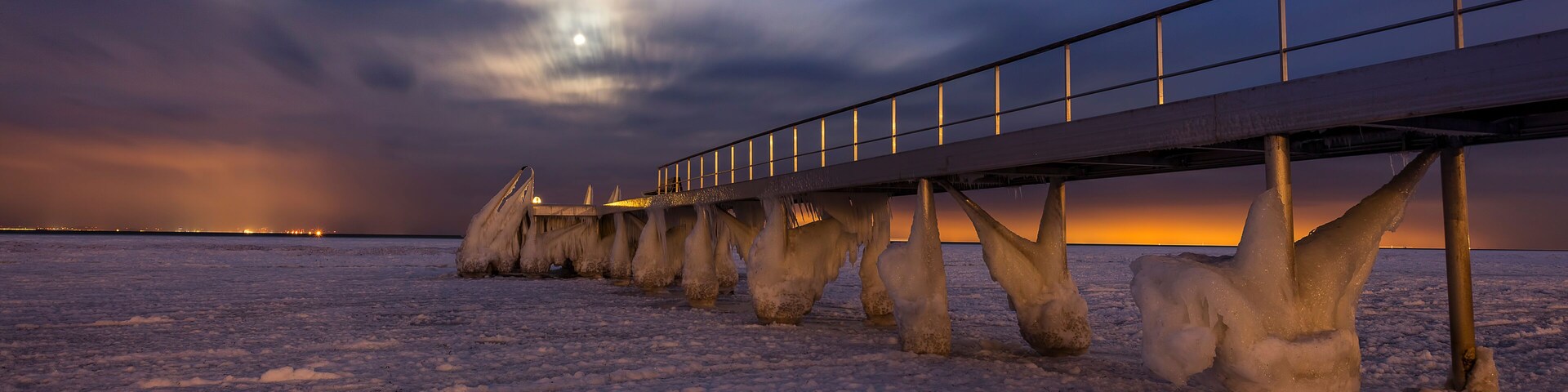 A frozen landscape with a bridge and ice formations.
