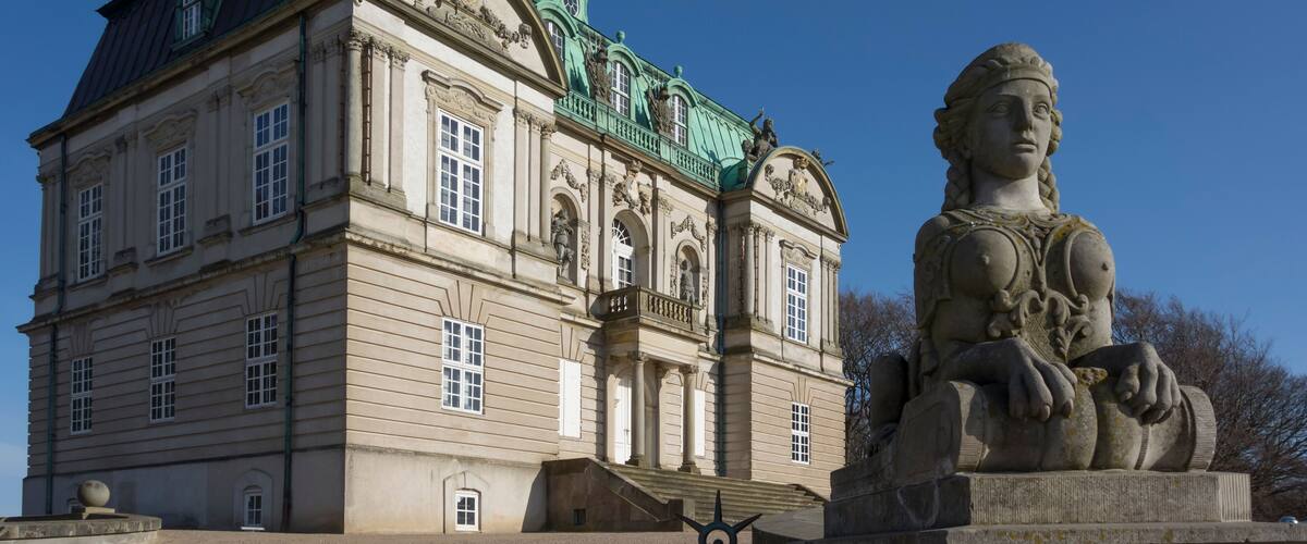 A historic building with ornate architecture and a statue in front.