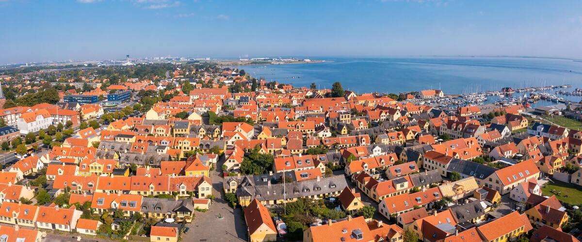 A coastal town with red-roofed houses and a marina.