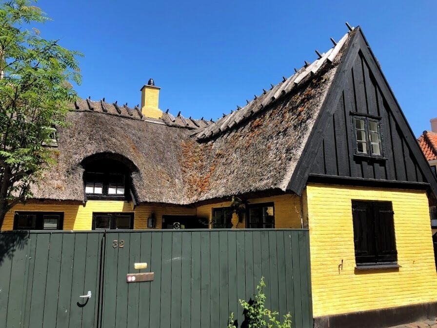 En traditionell byggnad med ett halmtak och gula väggar.