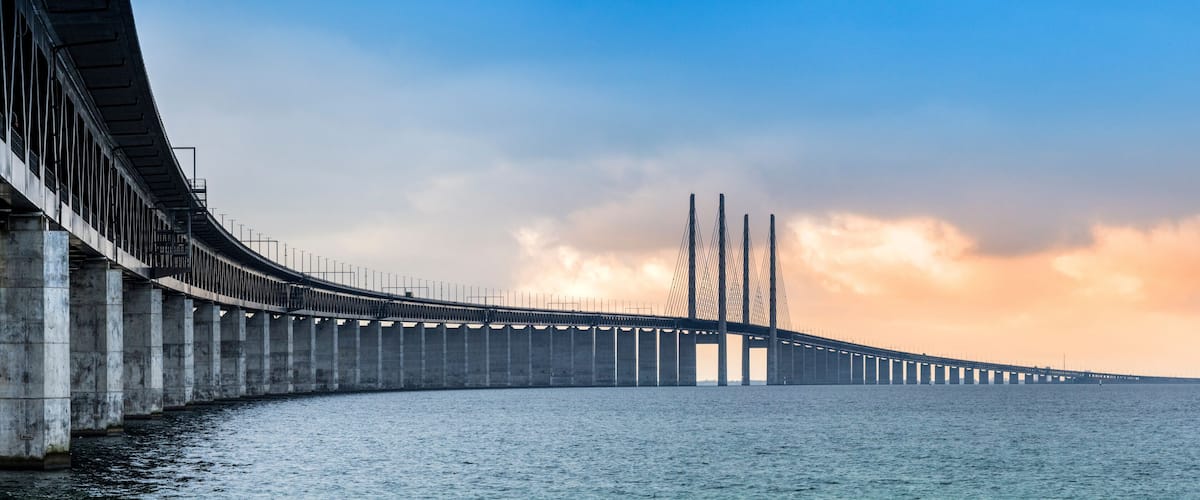 A long bridge spanning a body of water, with a clear sky and clouds in the background.