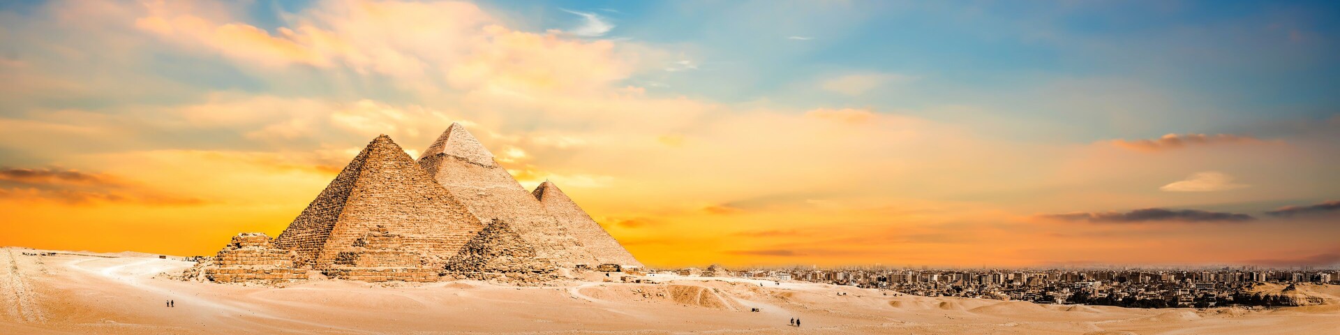 La Gran Pirámide de Giza con un paisaje desértico y el horizonte de una ciudad al fondo.