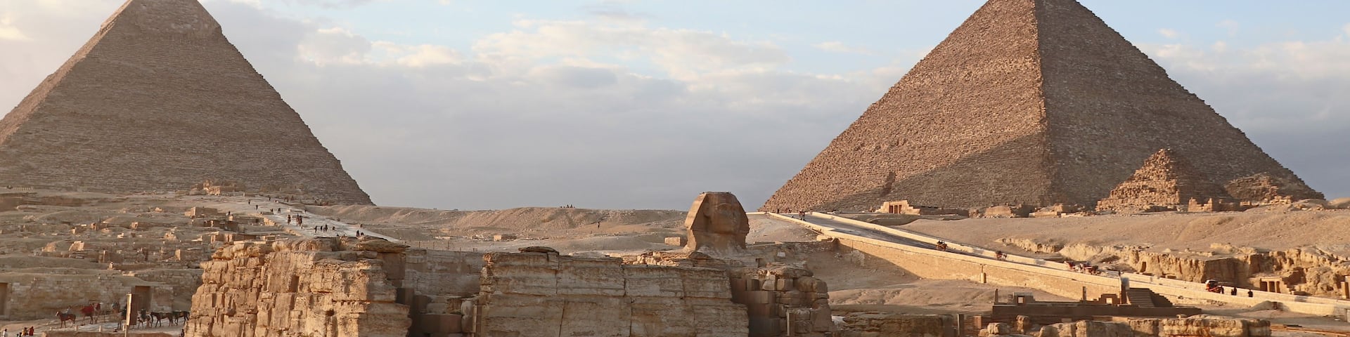 Two large pyramids, a desert landscape, and ancient ruins.