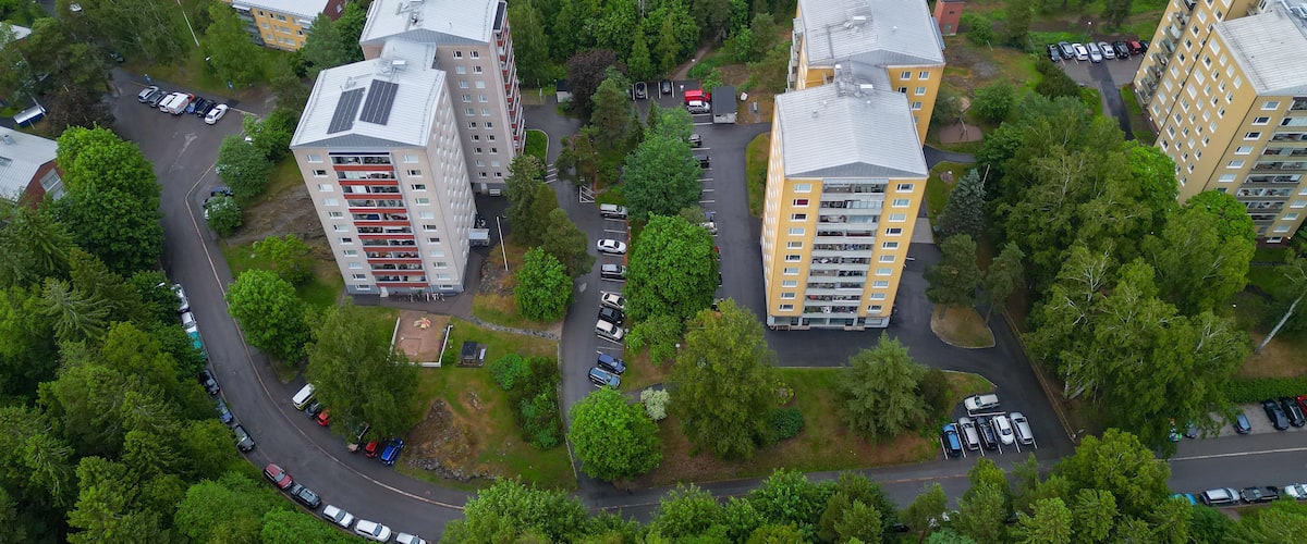 Ilmakuva asuinalueesta, jossa on kerrostaloja, teitä ja parkkeerattuja autoja.