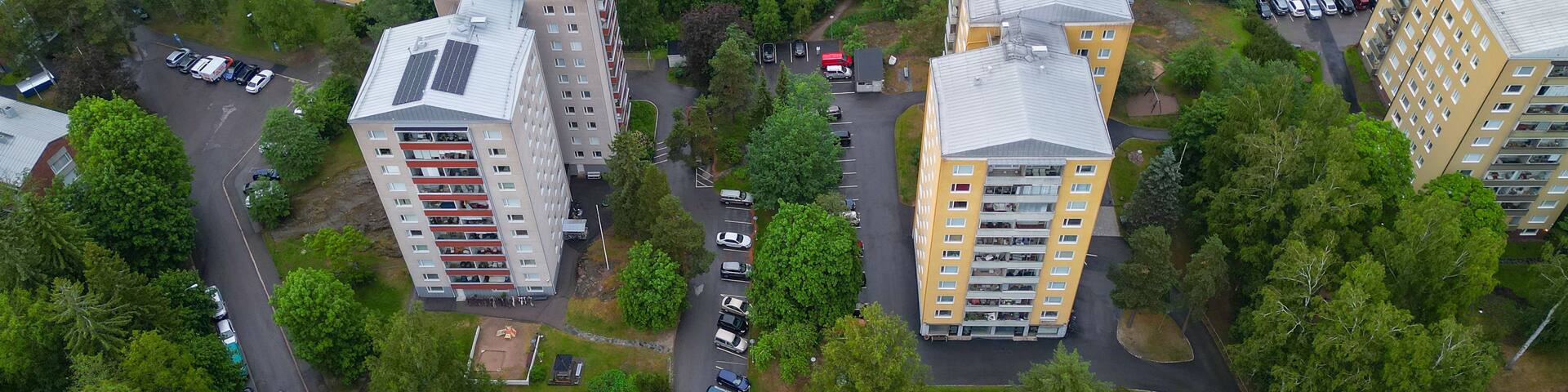 An aerial view of a residential area with apartment buildings, roads, and parked cars.