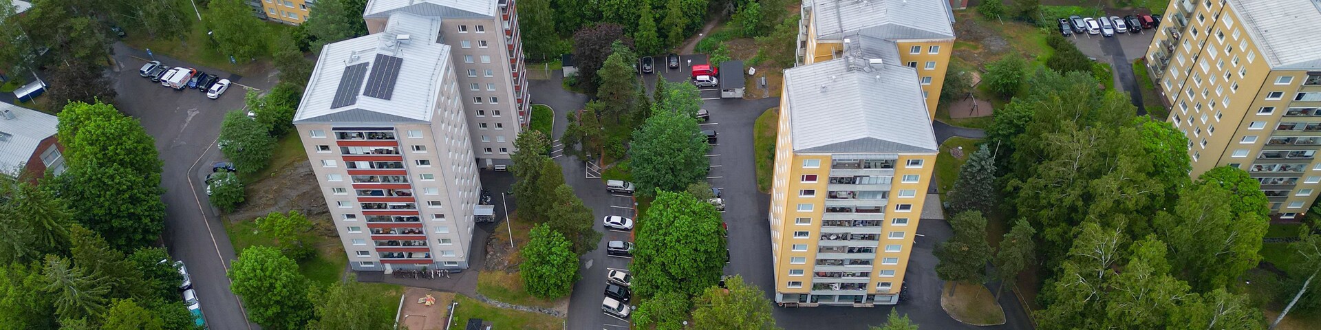 Vista aérea de um bairro residencial com edifícios de apartamentos, ruas e carros estacionados.