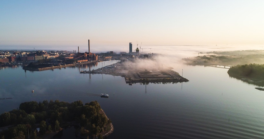 Teollisuusalue, jonka yhteydessä on suuri vesialue, silta ja sumuinen maisema.