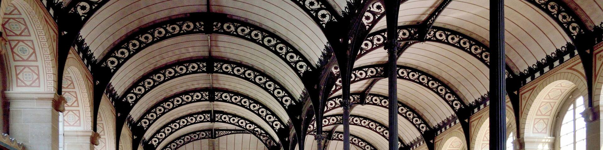 A large, ornate library with high ceilings, arched windows, and rows of bookshelves.