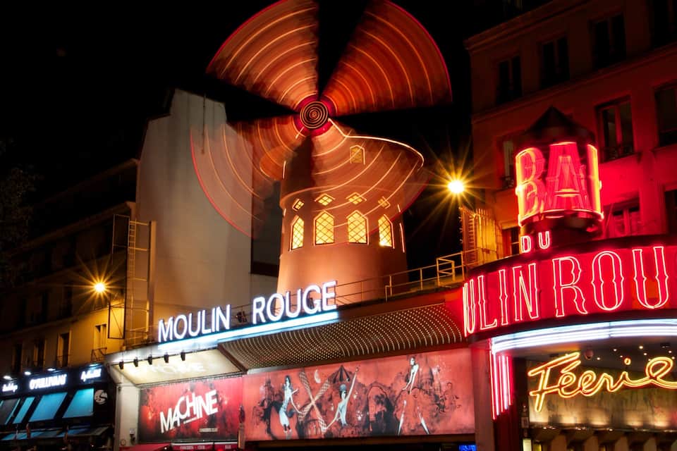 Moulin Rouge mit beleuchteter Beschilderung und einer großen Fächerkonstruktion.