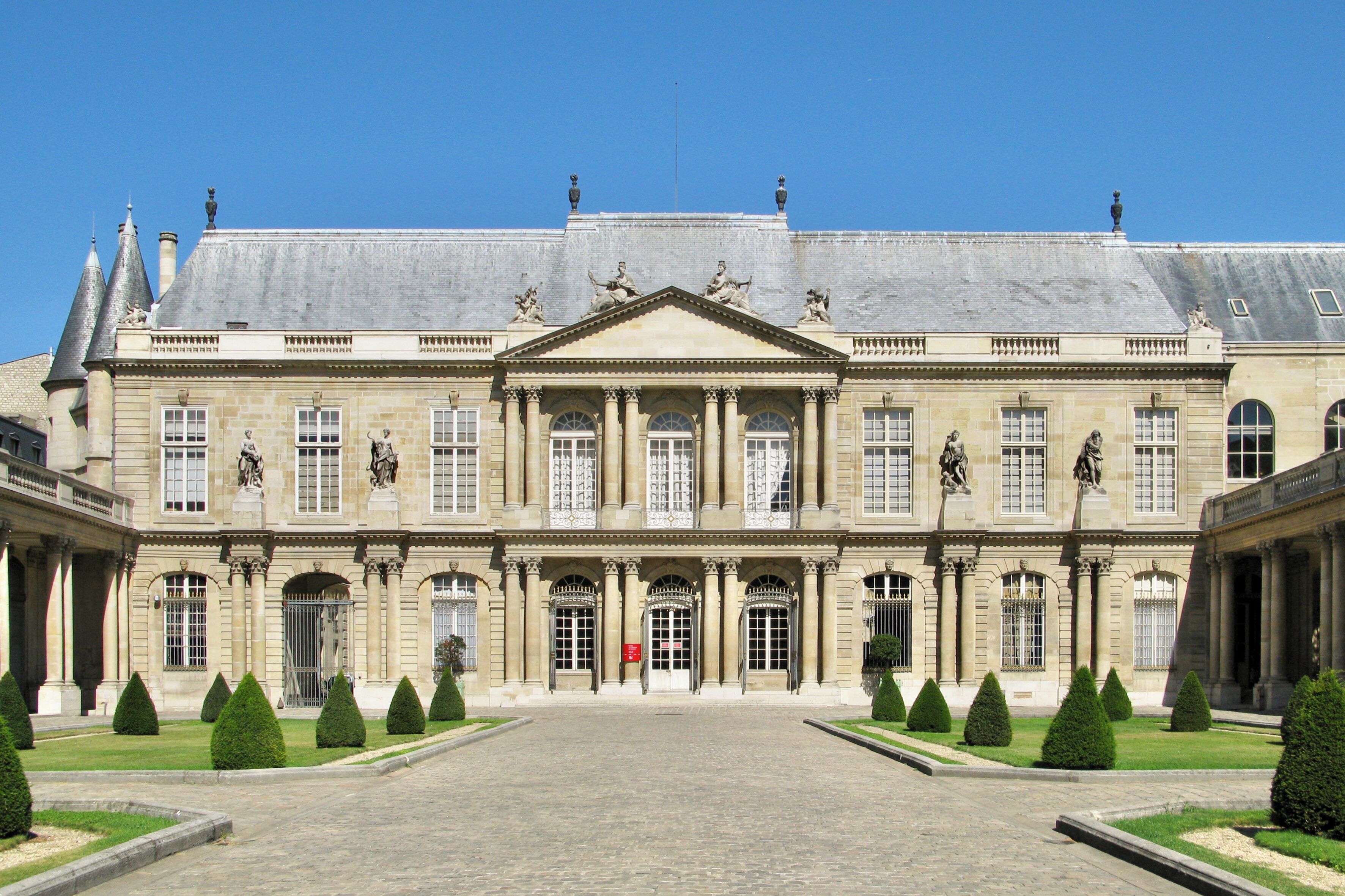 A large, historic building with a symmetrical facade, columns, and statues.