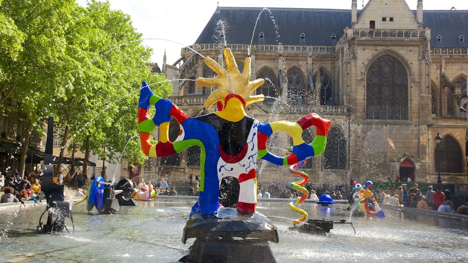 A colorful fountain sculpture in front of a historic building.