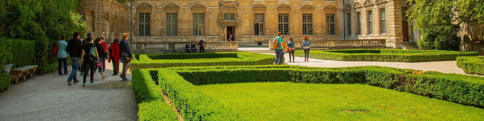 Marais featuring heritage architecture and a garden as well as a small group of people