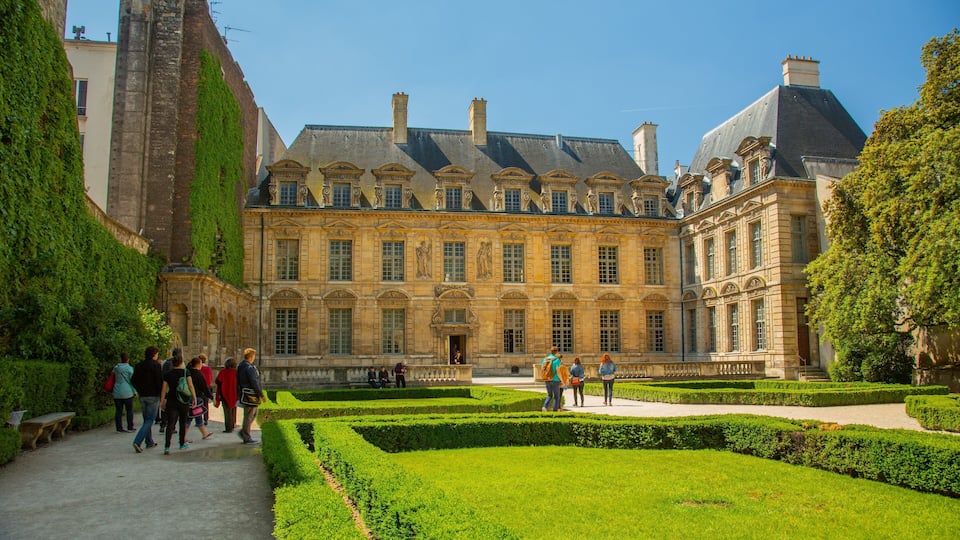 Marais featuring heritage architecture and a garden as well as a small group of people