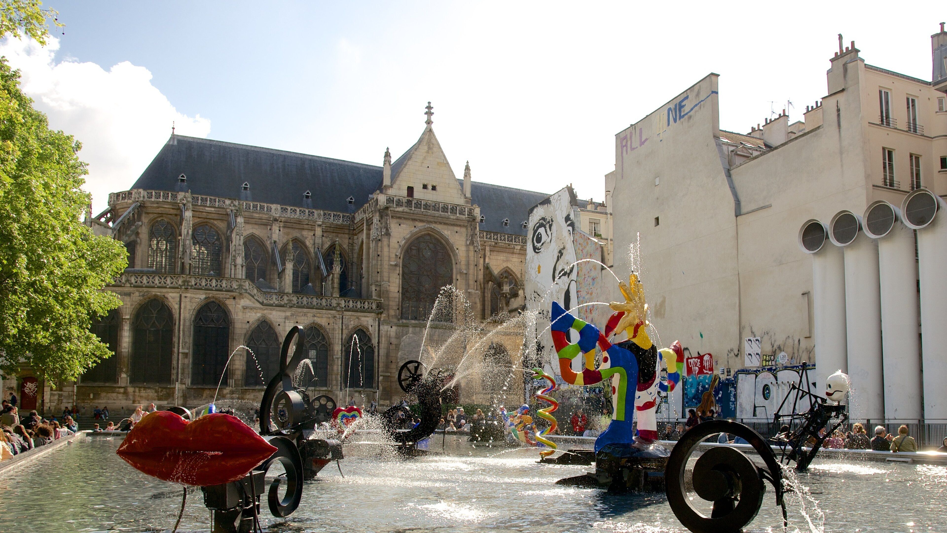 A fountain with water jets and a colorful float in front of a historic building.