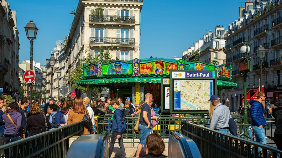 Une rue animée avec une galerie marchande aux couleurs vives et un panneau indiquant le chemin vers Saint-Paul.