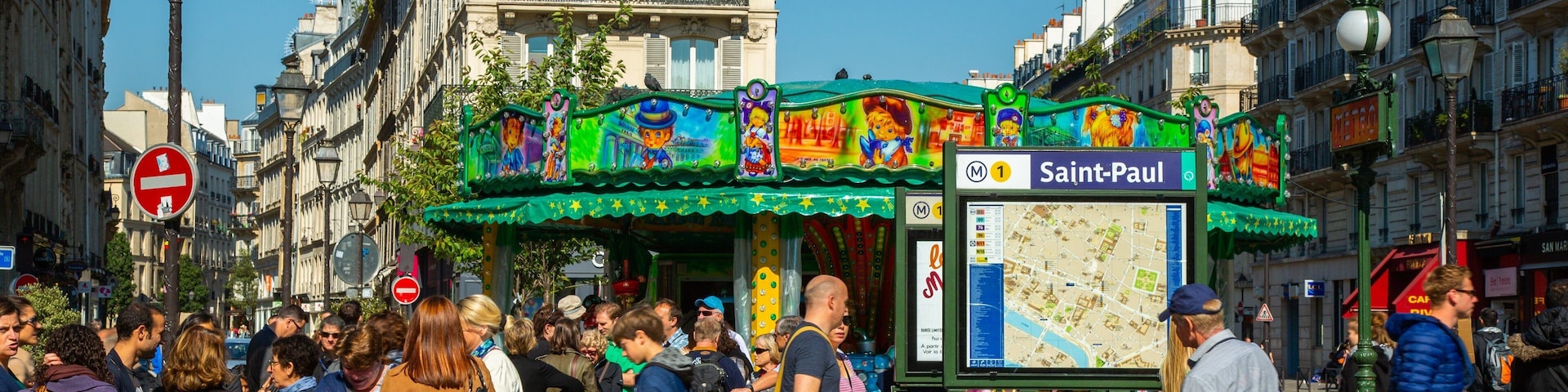 Escena de calle concurrida con un colorido arcade y un cartel con mapa de Saint-Paul.