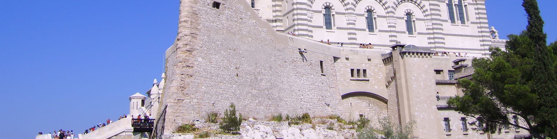 A large, historic building with a prominent tower and dome, surrounded by a stone wall.
